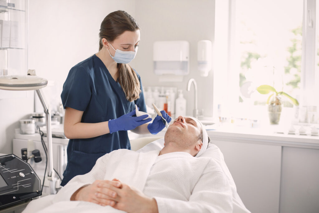 Aesthetican treating a man with safety mask in hygenic condition